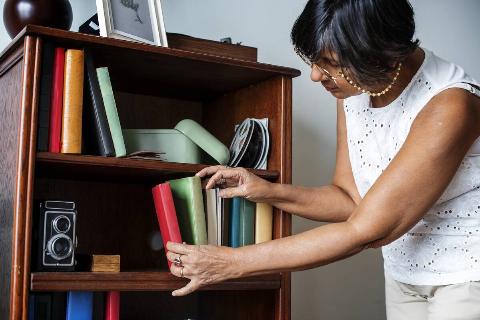 Woman cleaning bookshelf.