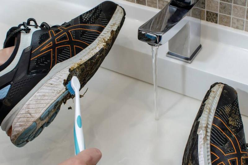кроссовки с зубной щеткой Руки чистят кроссовки зубной щеткой.
