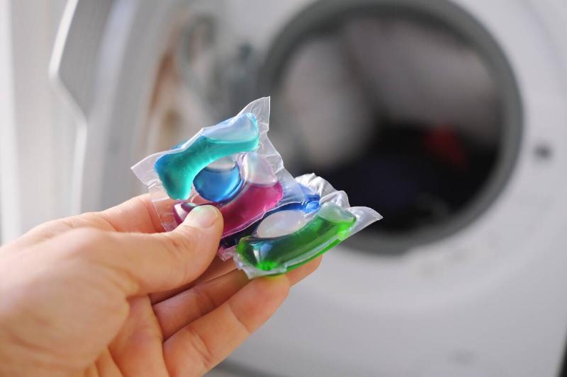 Laundry pods in front of a washing machine.
