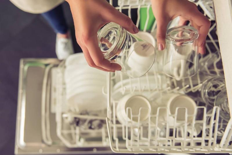 Woman loading dishwasher. 