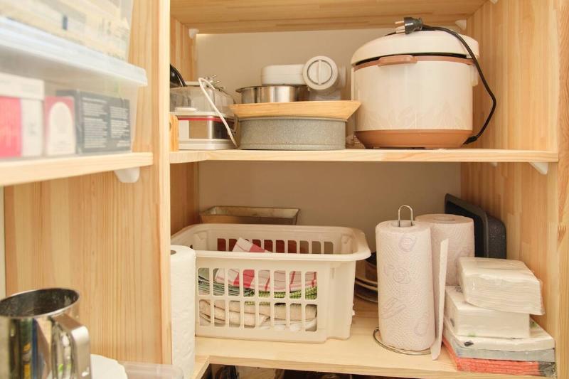 Appliances put away with other supplies in cupboards. 