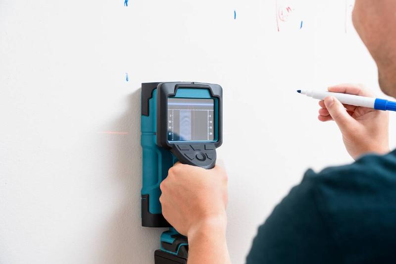 Worker marking studs using a wall scanner. 