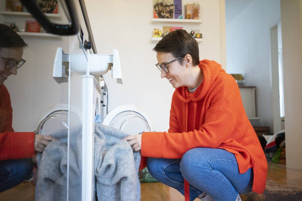 Woman putting thrifted clothes in dryer. 