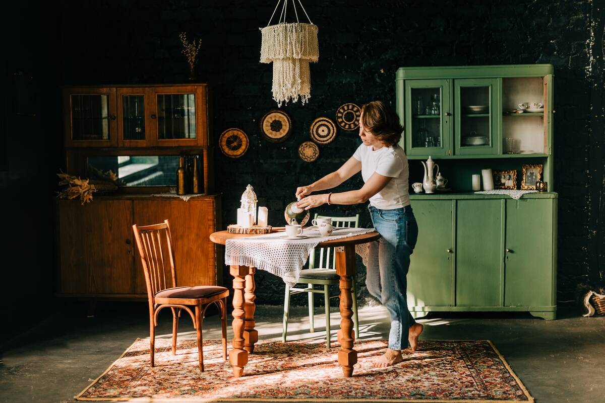 Young woman making tea in vintage-style kitchen.