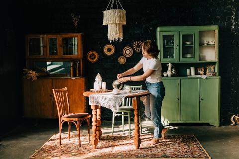 Young woman making tea in vintage-style kitchen.