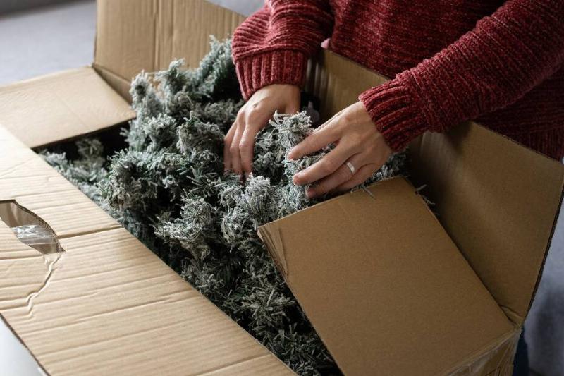 Woman putting fake Christmas tree in box. 