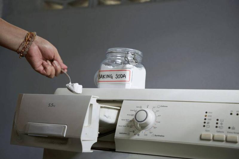 Person putting baking soda in washing machine.