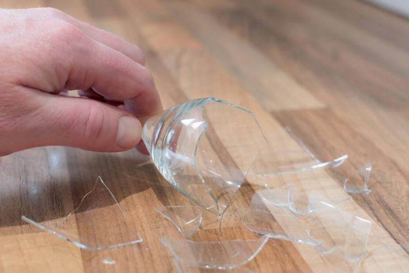 Hand picking up broken glass.