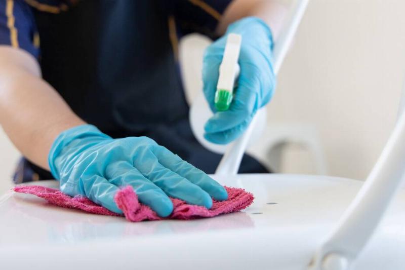 Persona spraying cleaning products and wiping with a cloth.