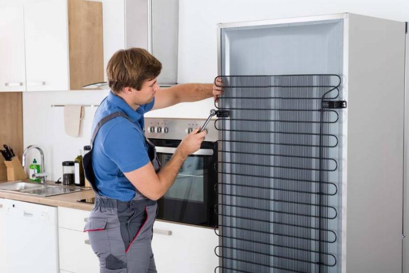 Man cleaning refrigerator coils. 
