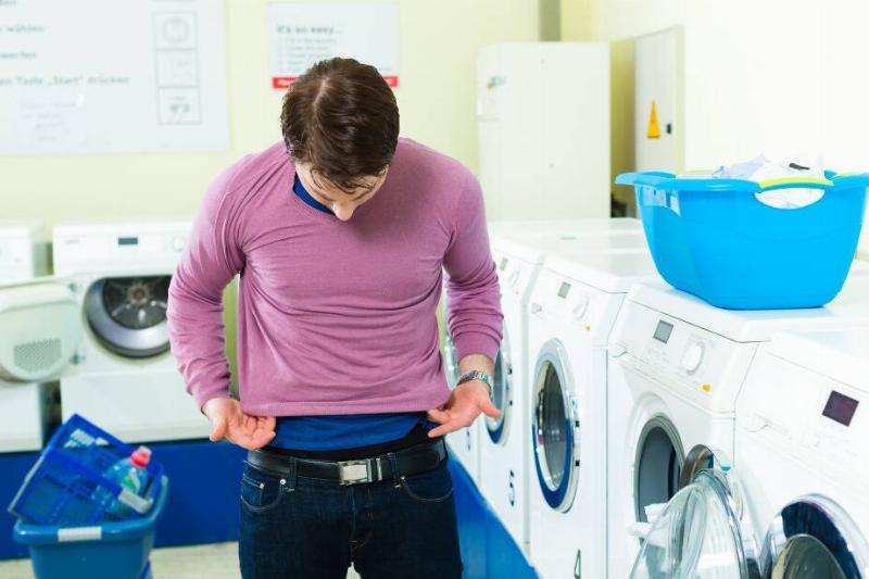 Man putting on shirt he shrunk in the wash. 