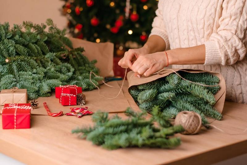 Woman wrapping up sections of fake Christmas tree. 
