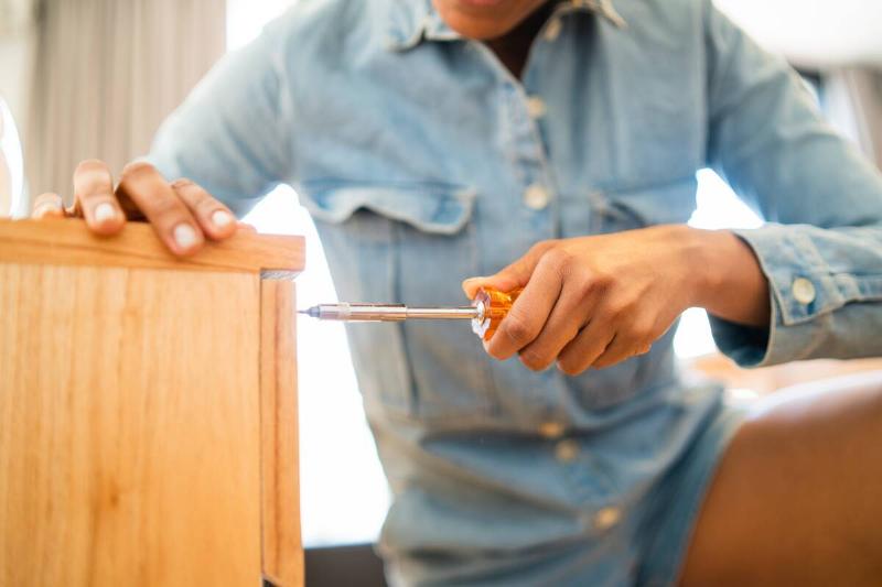 Person tightening screws on wooden drawer. 