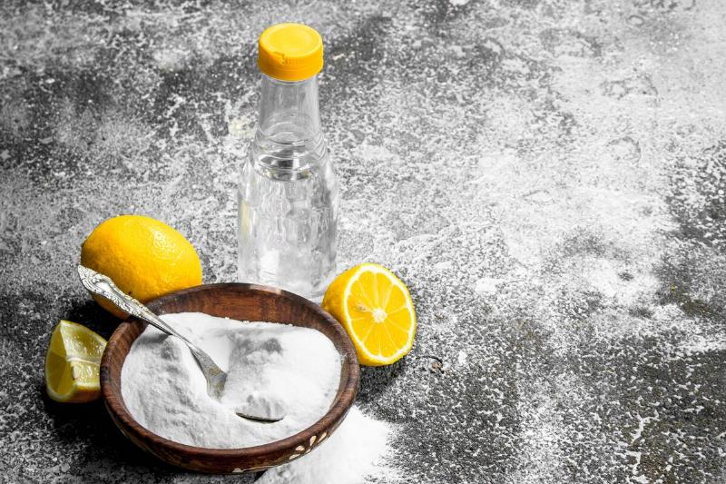 Baking soda, lemon, and vinegar on marble background. 