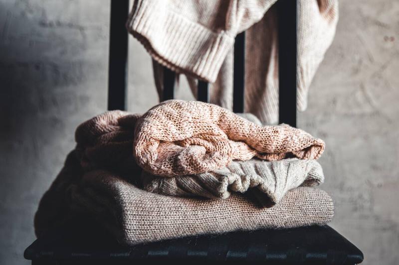 A chair with sweaters piled on it. 