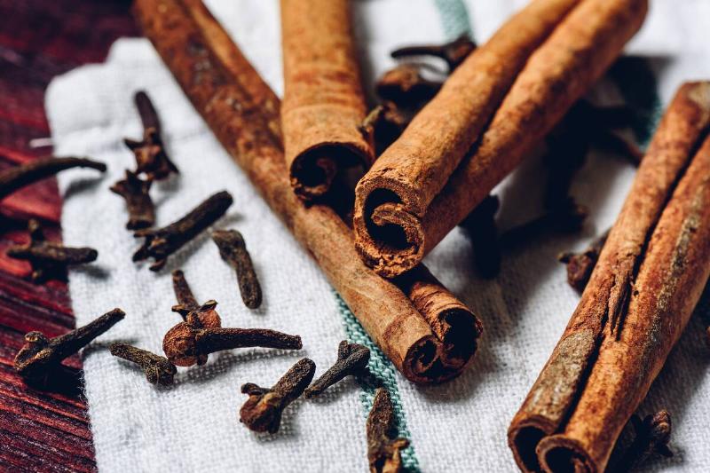 Cinnamon sticks and cloves on white kitchen towel.