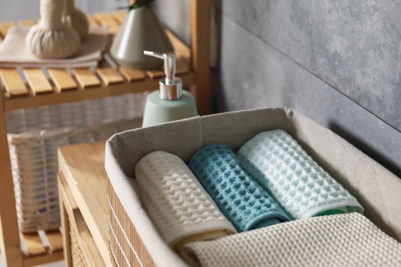 Clean waffle towels on wooden dresser in bathroom.