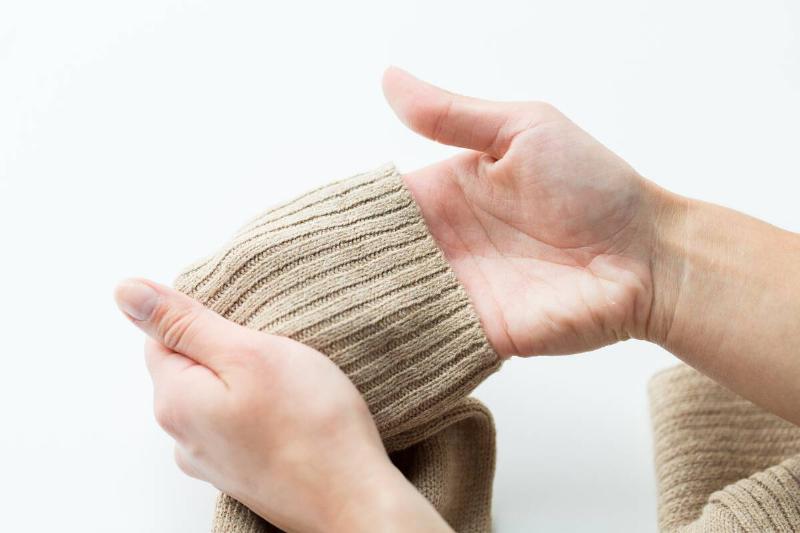 Hands gently stretching out cuffs of a sweater. 