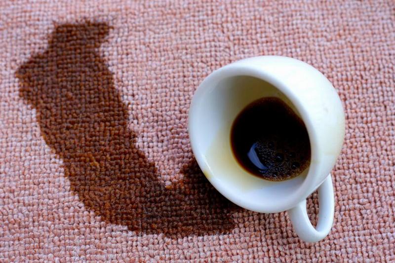 Coffee spilled from white cup on the carpet.