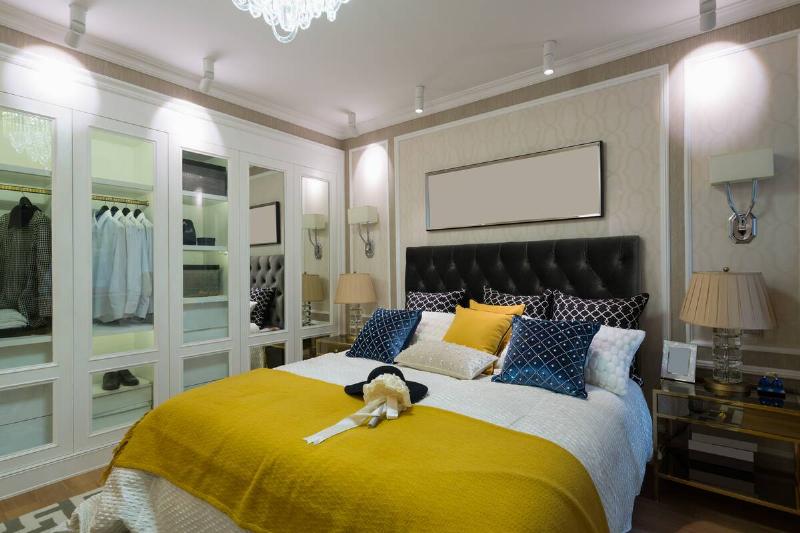 A bedroom with yellow accent pillows and blankets. 