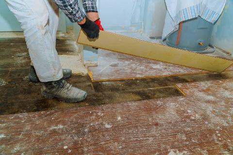 A man removing old flooring in a house. 