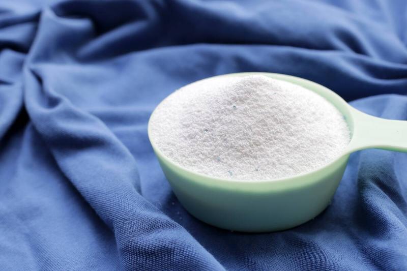 Washing soda in measuring cup on laundry. 