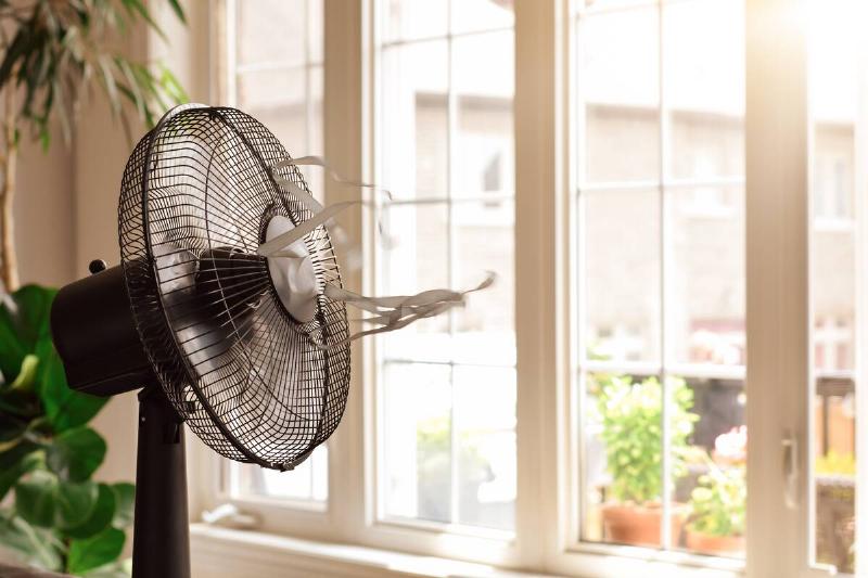 Electric cooling fan with blowing ribbons in front of a window.