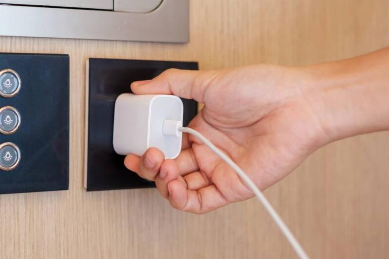 Person plugging in phone charger.