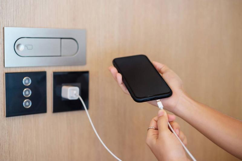 Hands plugging in a phone to charge. 