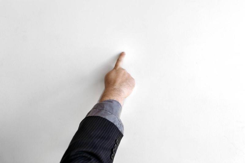 A person using their finger to put paint on a wall. 