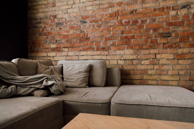 Exposed brick behind a couch in a living room. 