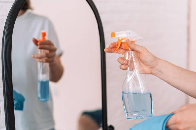Person spraying ammonia cleaner on mirror. 