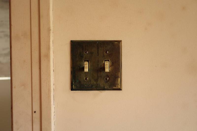 A dirty switch plate on the wall of a house. 