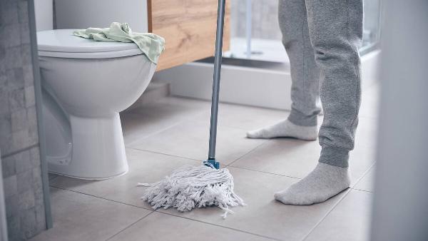 Man in socks mopping the bathroom floor. 