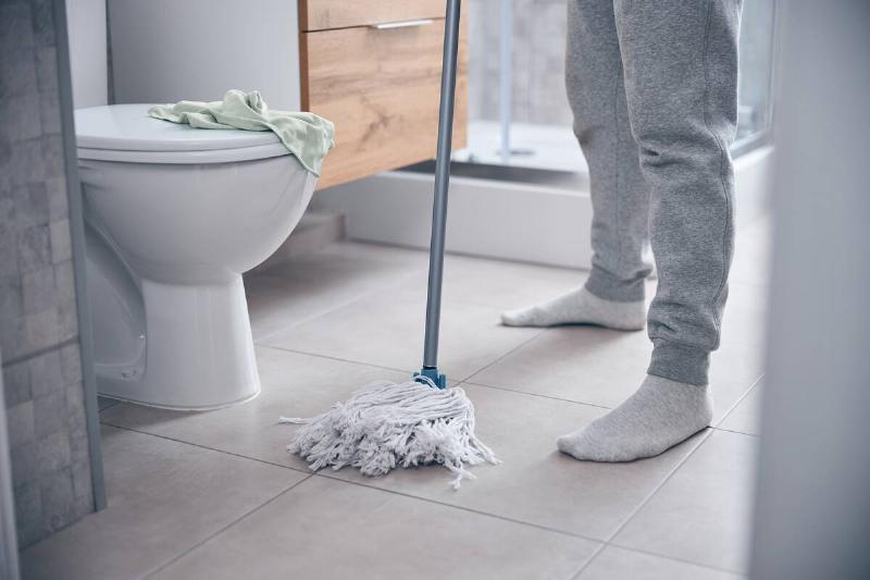 Man in socks mopping the bathroom floor. 