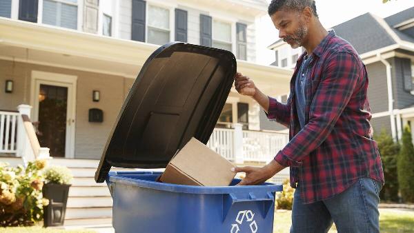 Man putting cardboard in recycling.