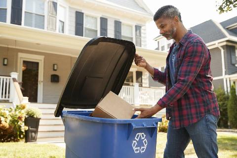 Man putting cardboard in recycling.