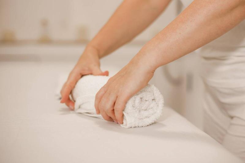 Woman pressing water out of clothes wrapped in a towel.