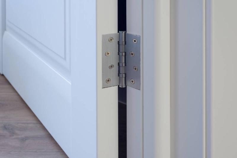 Metal hinge on white wooden door. 