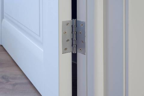 Metal hinge on white wooden door. 
