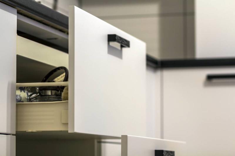 Open kitchen drawers with plates and cups dishes.