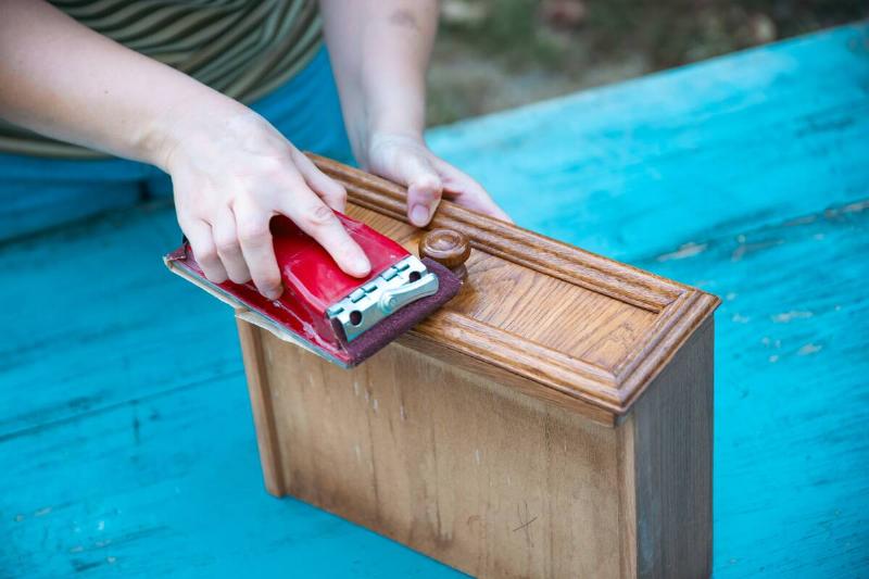 Sanding down problem areas on a wooden drawer. 