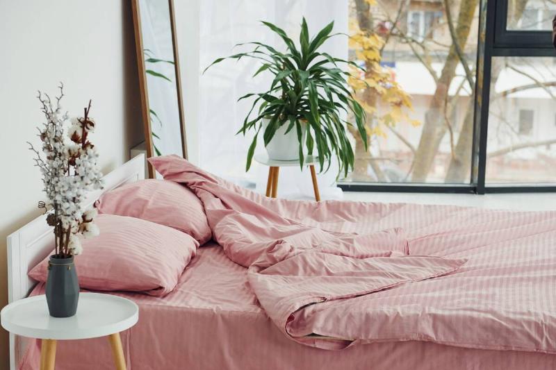 Pink colored bedding on a bed with flat pillows.
