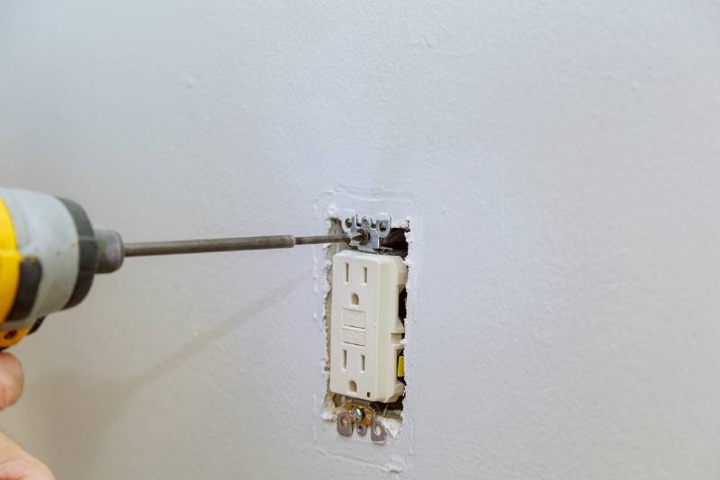 Person screwing outlet into wall. 