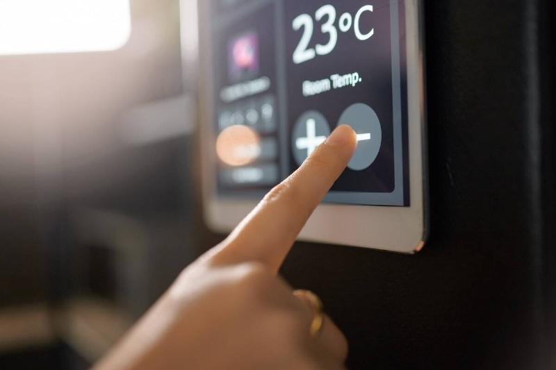 Hands adjusting temperature on thermostat. 