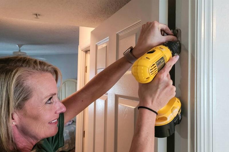 Woman tightening screws on door hinge. 