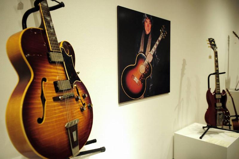 Two electric guitars on display, with a poster of a man holding one between them
