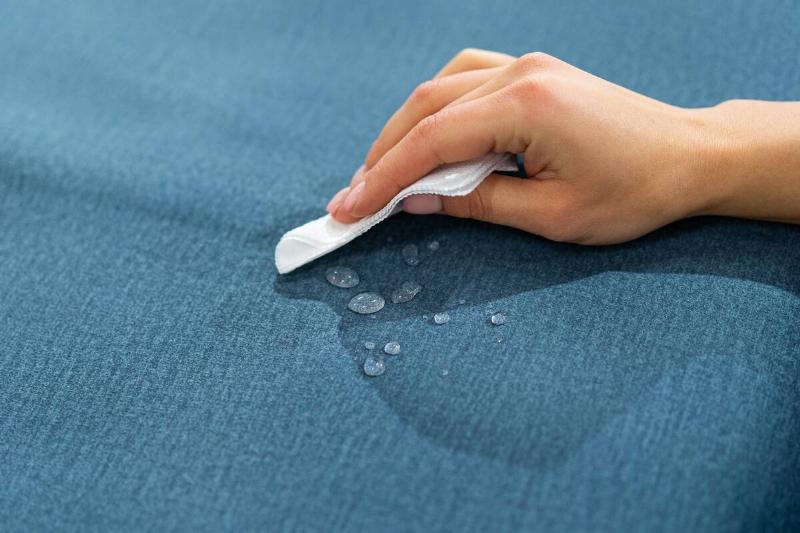 Hands wiping water off a waterproof sofa cover. 