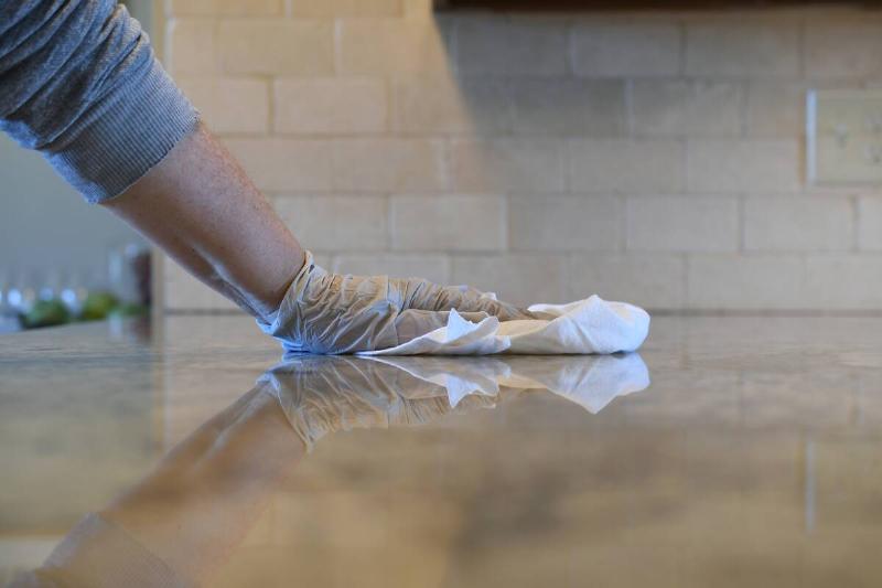 A hand wiping a granite countertop. 