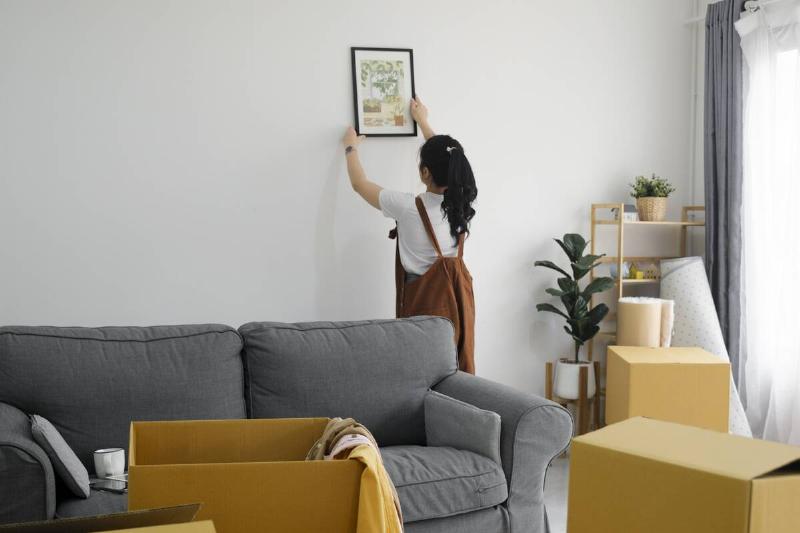 Woman decorating her house and putting up art.